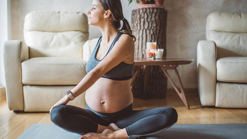 Pregnant woman stretching and practising yoga at home