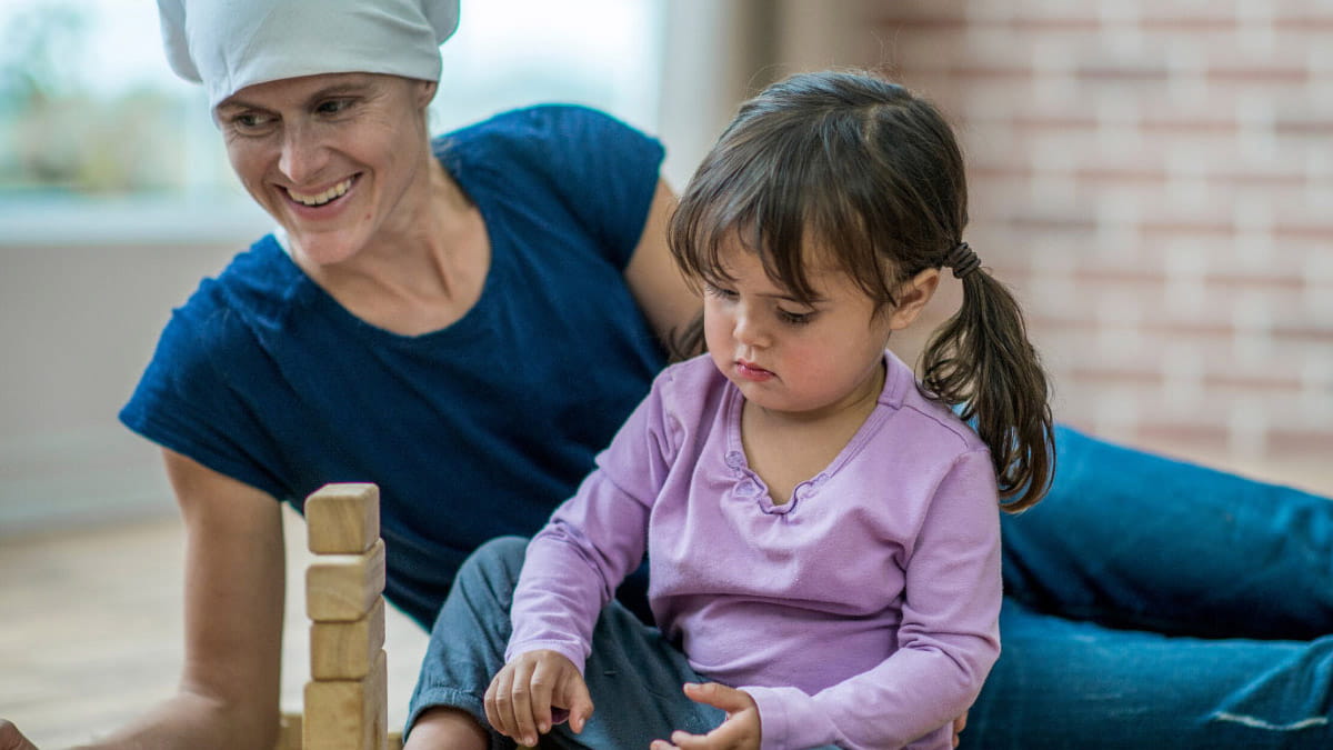 Mother undergoing chemo treatment playing with toddler daughter at home