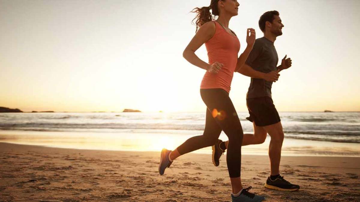A healthy man and woman running along the beach