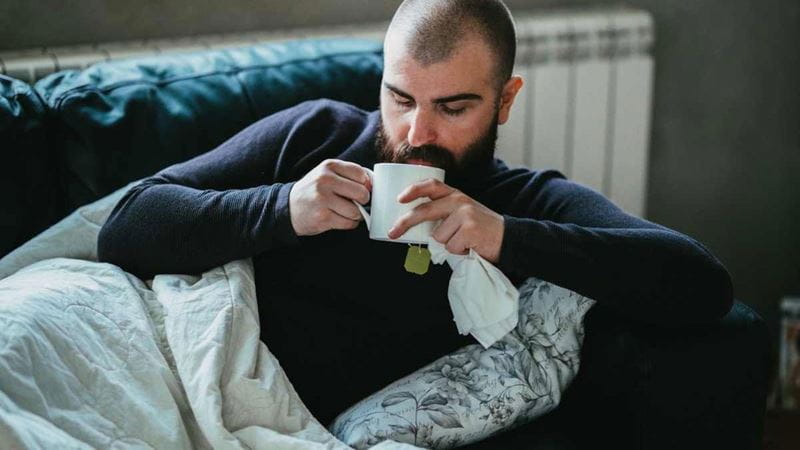 Man sitting on couch with cup of tea
