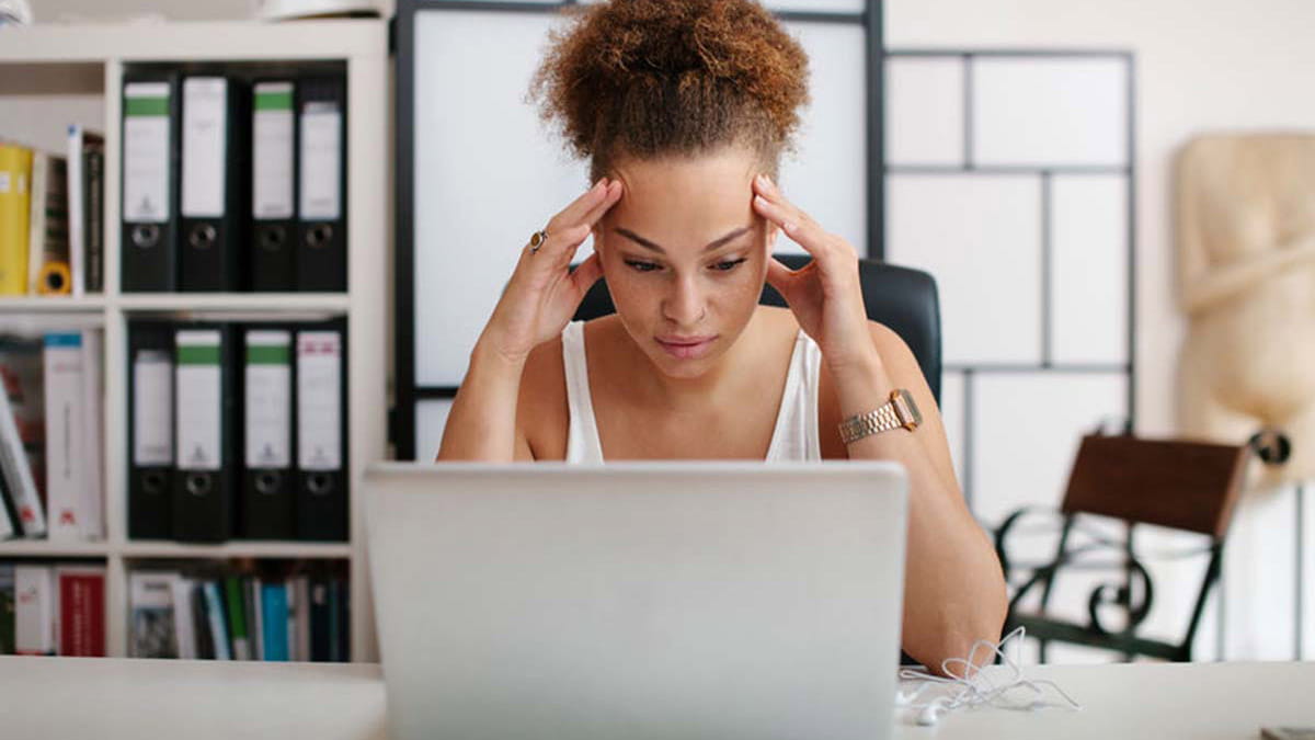 Woman in office straining her eyes reading laptop