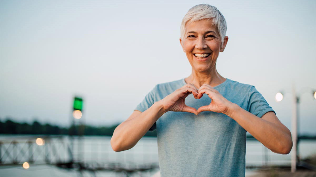 Smiling senior woman making a heart in front of her chest