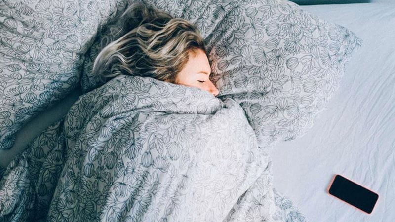 Woman snuggled up in doona