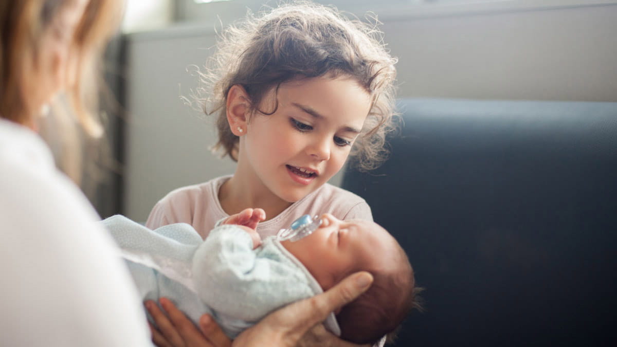 Young girl and mother holding newborn