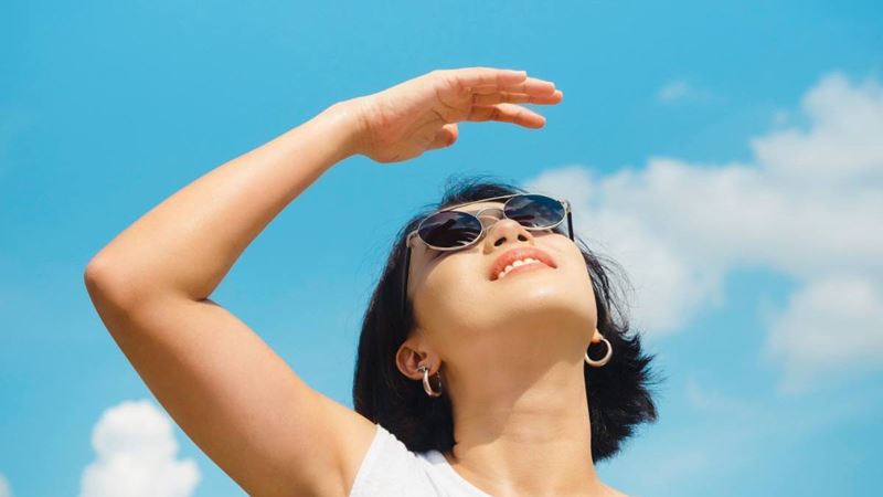 Woman in sunglasses looking up at the sky.