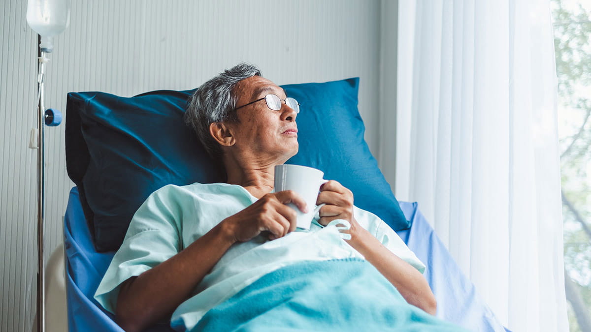 Man with a cup of tea in hospital bed