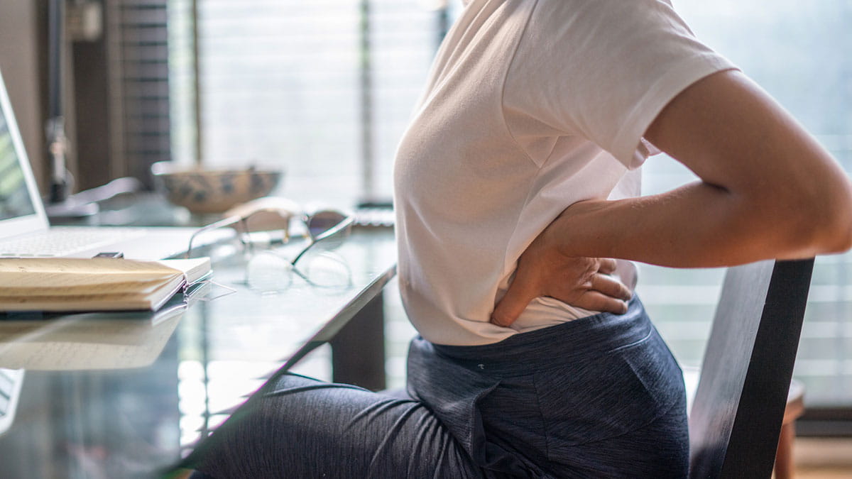 Woman sitting at her desk stretching her back