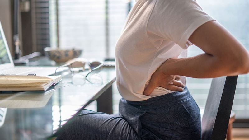 Woman sitting at her desk stretching her back