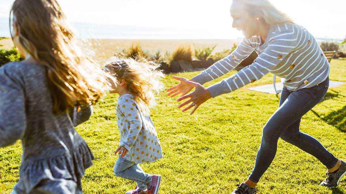 Mother playing chasey with young children