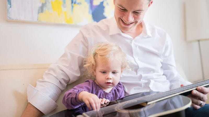 Father and young daughter playing a guitar