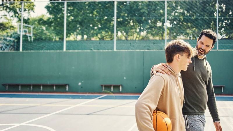 Father talking to son on basketball court