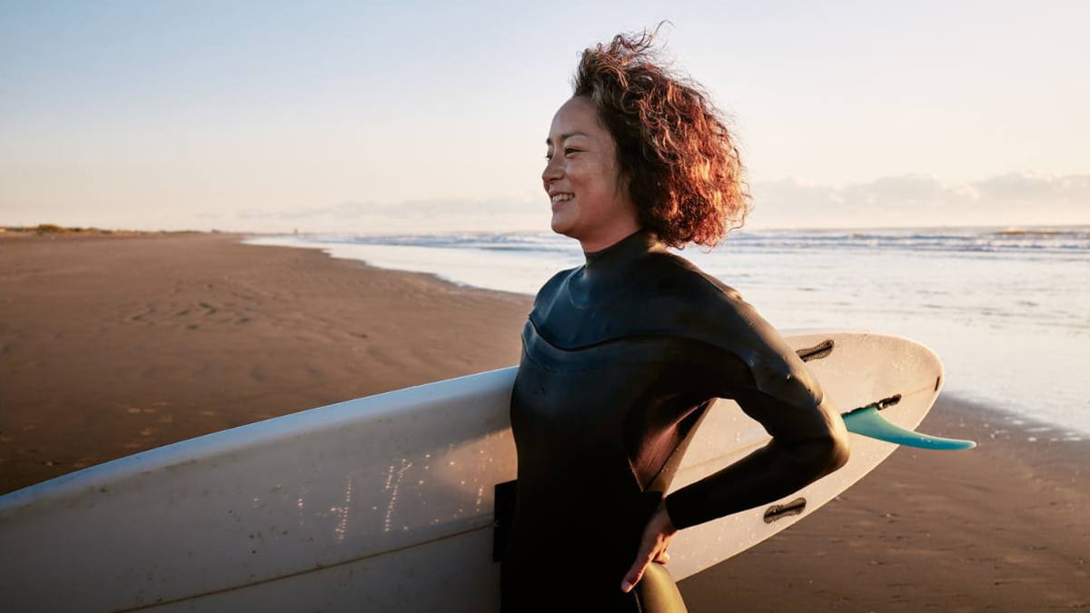 Woman at the beach holding a surfboard