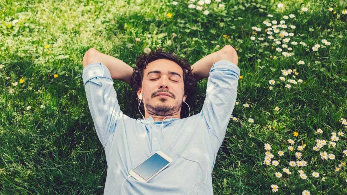 A young man relaxing on the grass listening to music