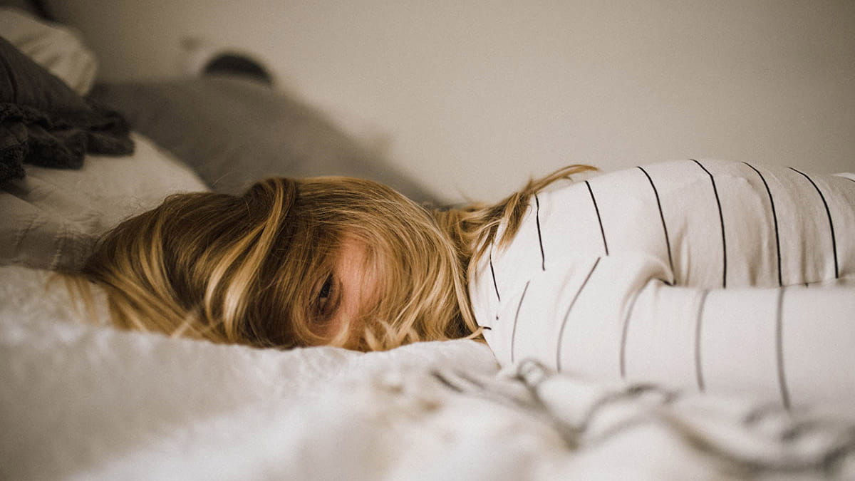 Woman lying face down on bed awake