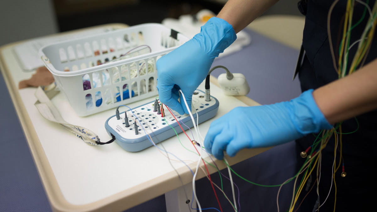 Gloved hospital worker setting up wired equipment