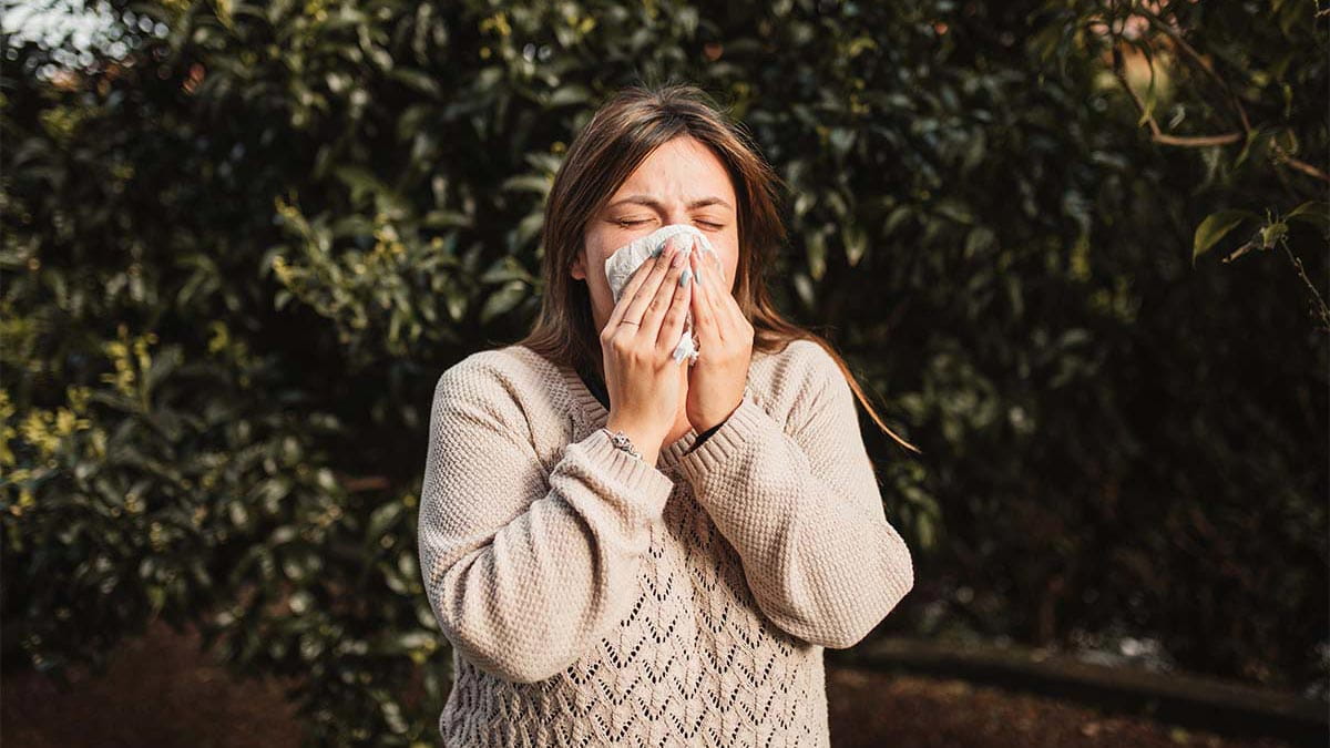 Woman sneezing in backyard