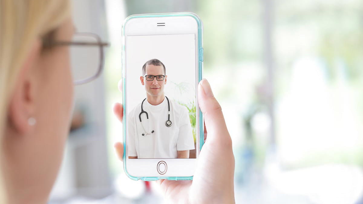 Woman holding phone with doctor on screen