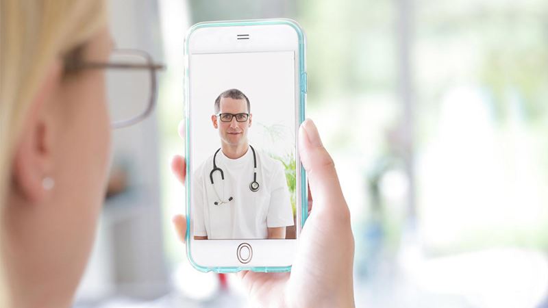 Woman holding phone with doctor on screen