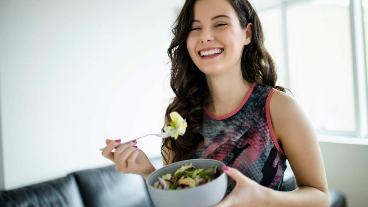 a young woman eating a healthy salad after a workout