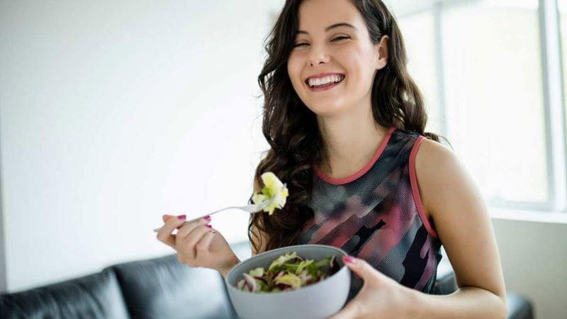a young woman eating a healthy salad after a workout