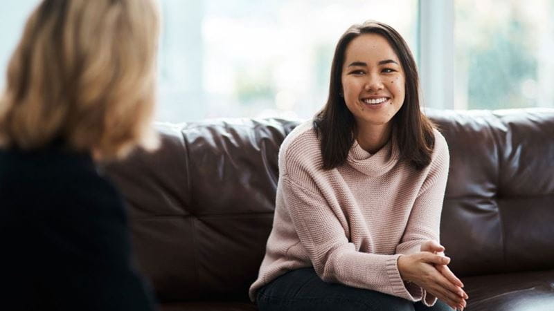 A young woman sitting on a couch and talking to the psychologist