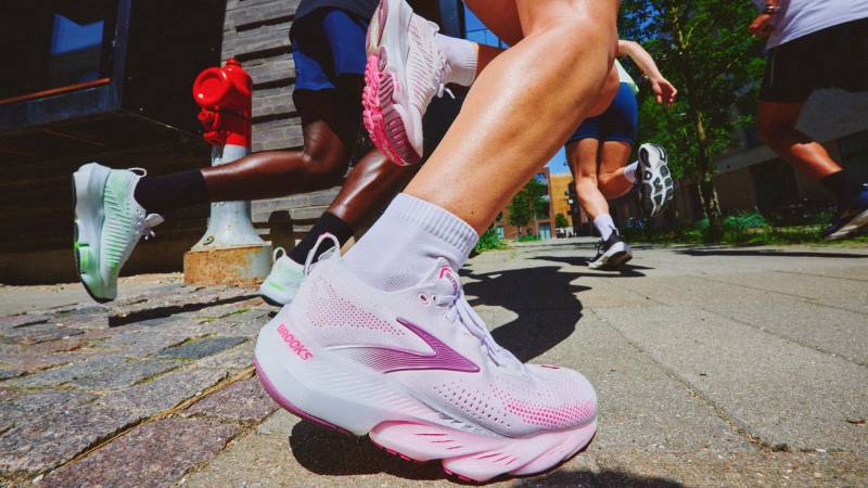 Close up shot of a pink and white Brooks running shoe