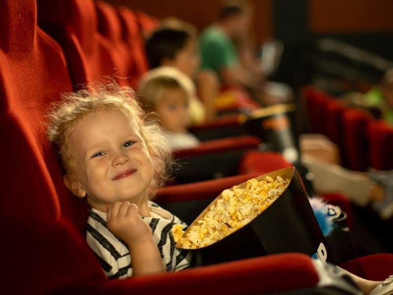 A child watching a movie in the cinema and eating popcorn