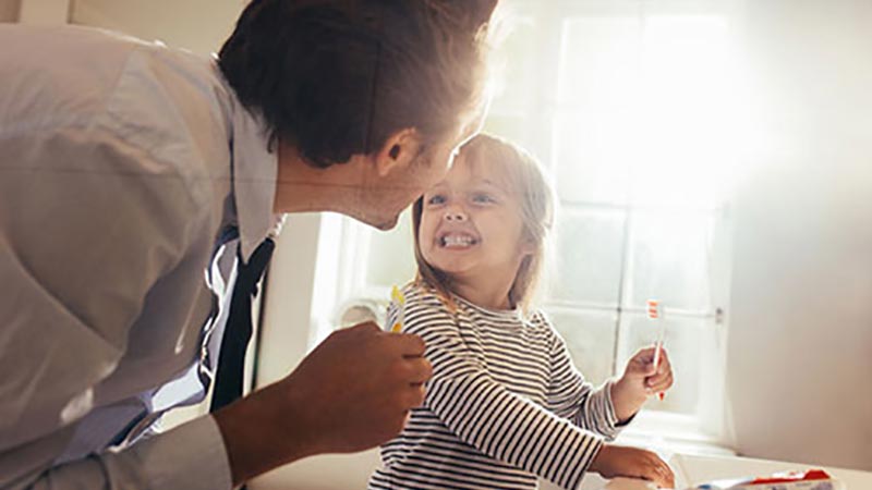 Young girl and dad comparing brushed teeth