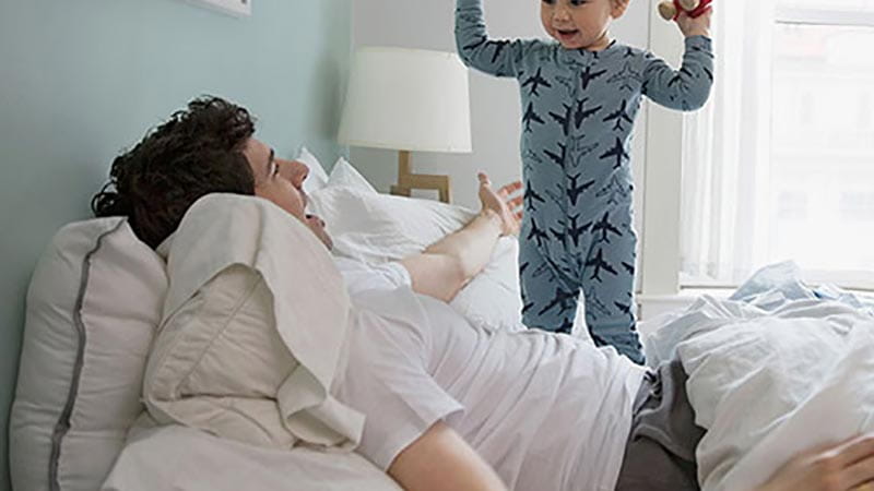 Dad and son playing on bed