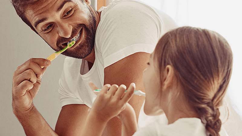Dad brushing teeth with daughter