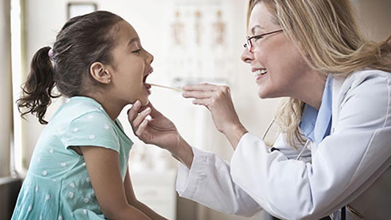 Doctor examining young girls tonils
