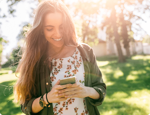 Young woman outside smiling while staring at her mobile phone