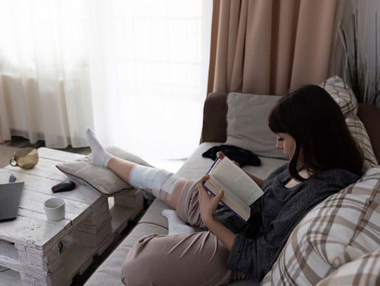 Woman sitting on couch reading book