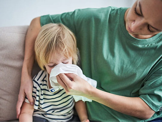 Mother helping child with cleaning nose