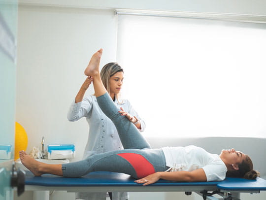 Physiotherapist stretching patient leg