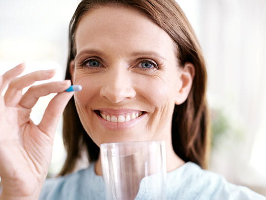 Woman smiling with a pill