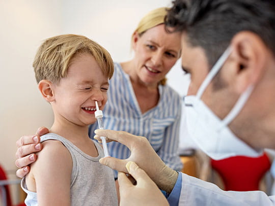 Young boy getting nose checked by doctor
