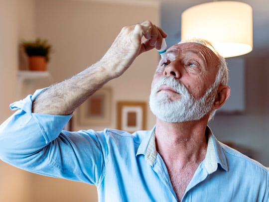 Mature man putting eye drops in