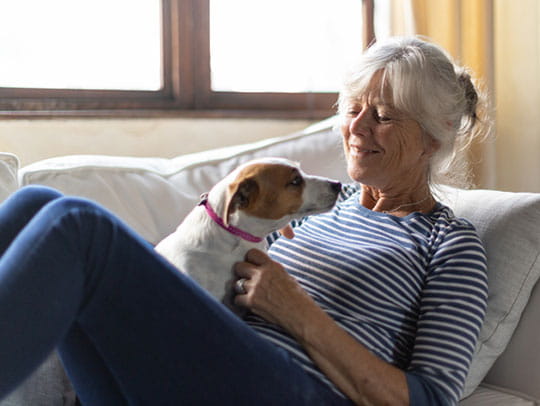 Older woman sitting on couch with dog