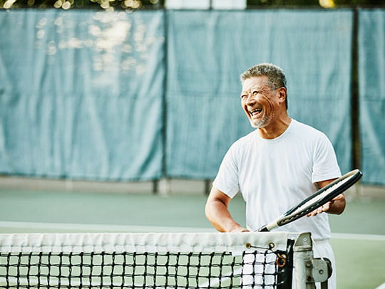 Older man smiling playing tennis