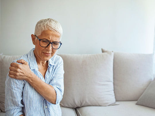 Elderly woman holding shoulder