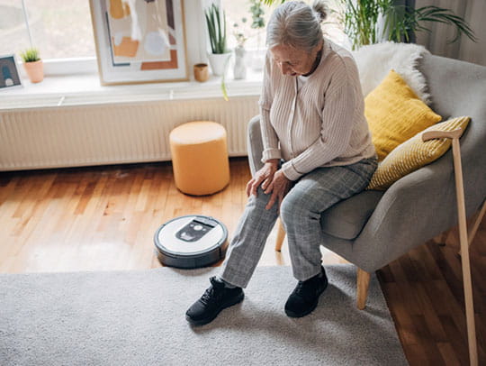 Older woman sitting down holding knee