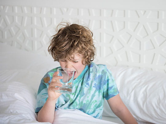 Child drinking water in bed