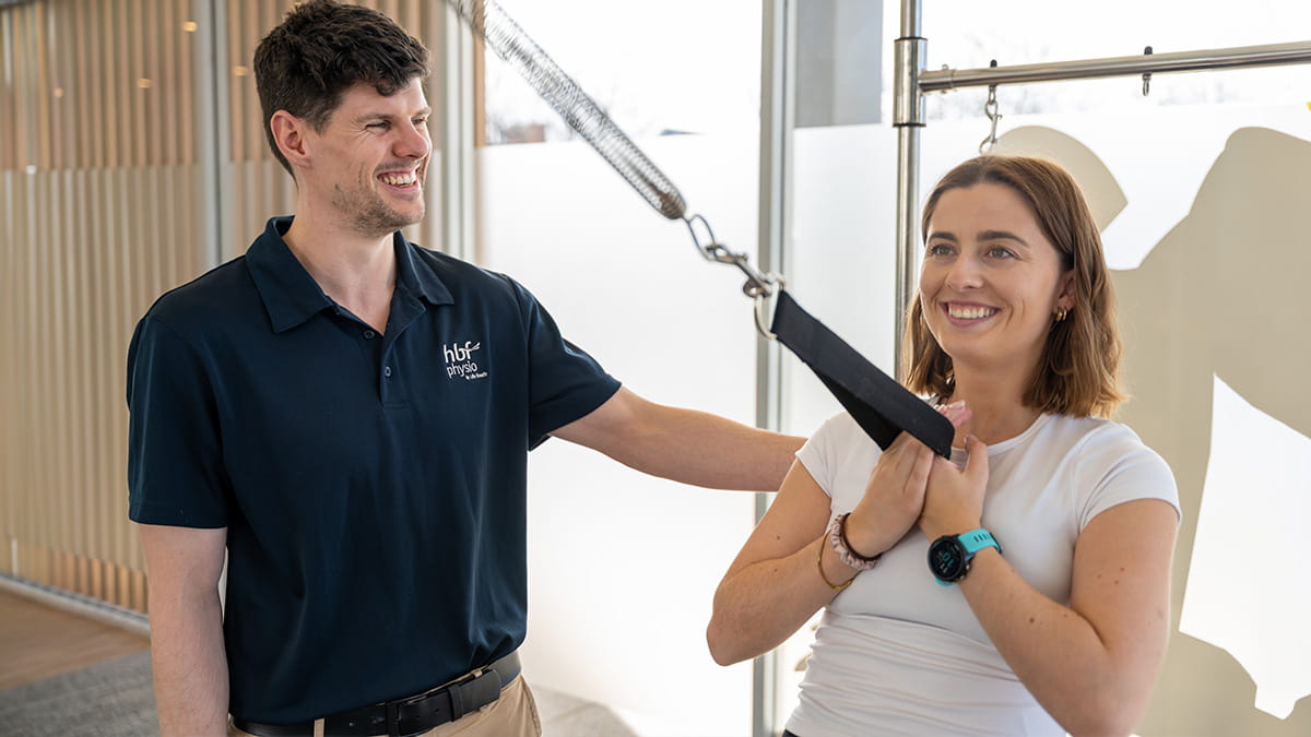 A woman exercising alongside a HBF physiotherapist