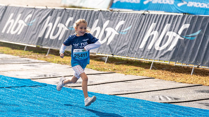 Young girl running through the finish line at run for a reason
