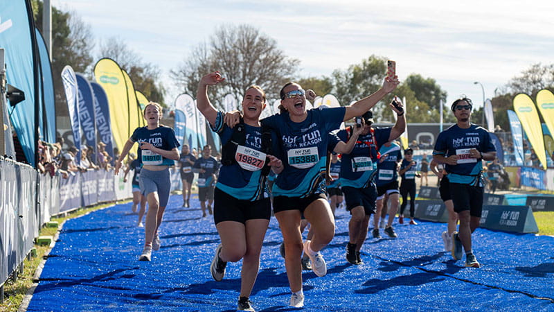 Two HBF Run for a Reason participants taking selfies as they cross the finish line