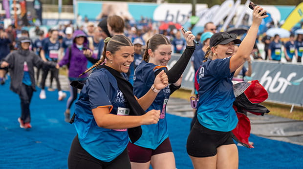 Team of three women crossing the finish line holding hands