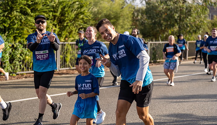 Father and daughter smiling as they run past the camera