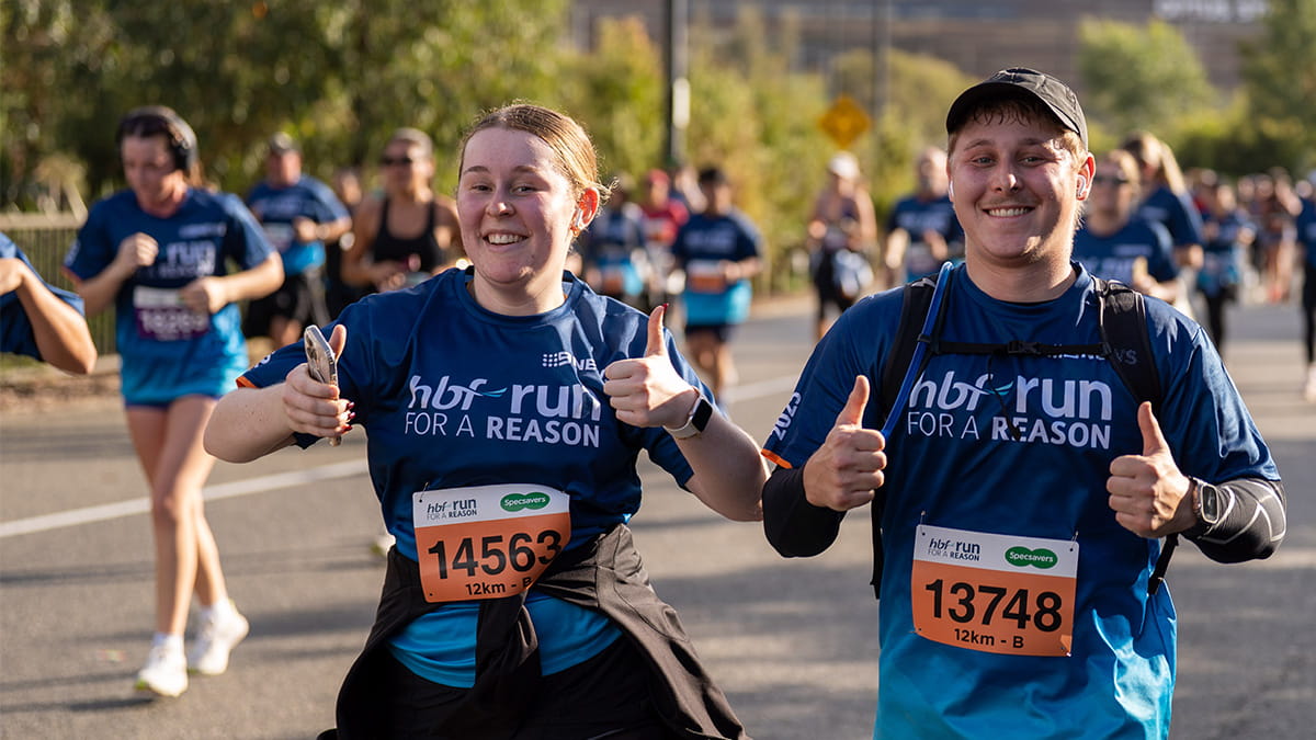 Young female and male participants giving thumbs up as they run past