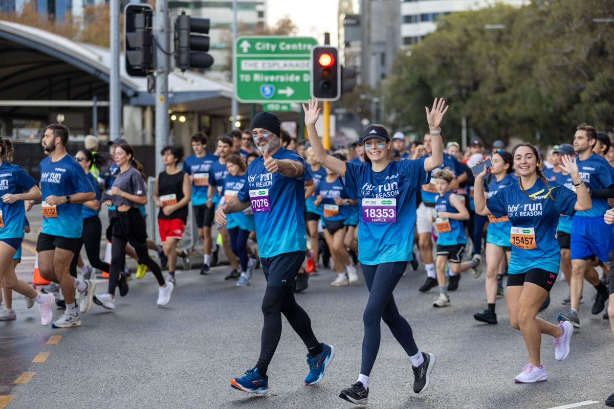 Run For a Reason participants waving as they run through the intersection